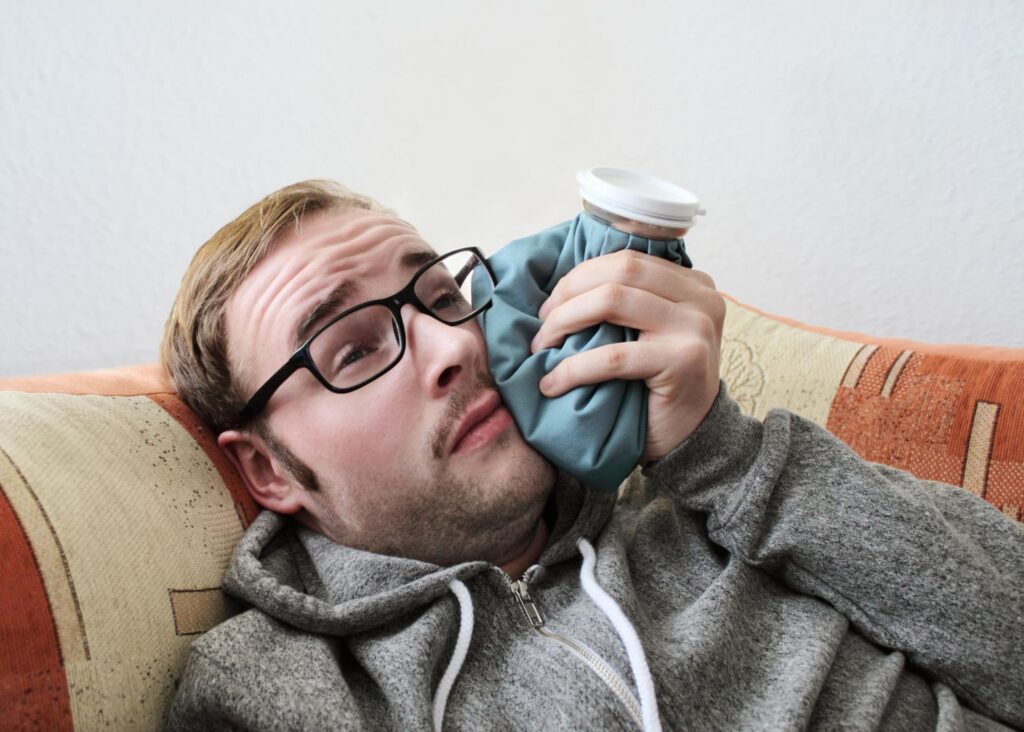 Man laying on couch post op recovering from wisdom teeth removal.