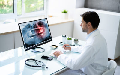 Dr. Sits at a Santa Monica Oral Surgery Center desk examining an x-ray of wisdom teeth.